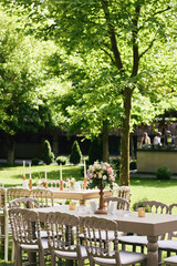 Charming Outdoor Garden Event with Wooden Tables, Soft Floral Decor, and Natural Greenery Ambience