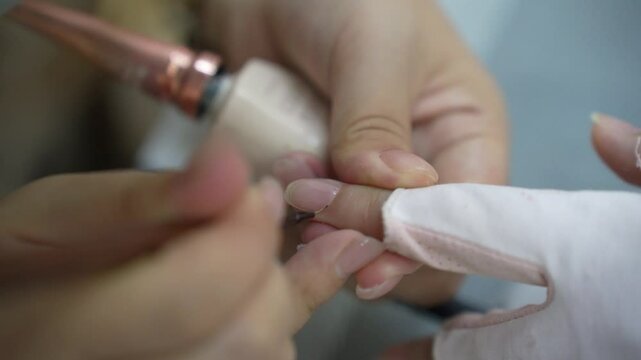 Closeup of professional beautician manicure master polish nail. Woman getting nail manicure. Cover the nails by transparent  varnish. Nail manicure process in a beauty salon.
