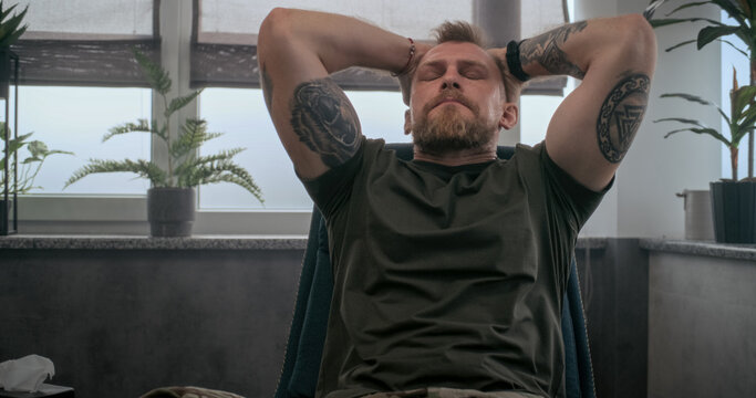 Dolly shot of shocked soldier with contusion or PTSD sitting in chair and crying. Military man during psychological rehabilitation or therapy session with psychologist. Post traumatic stress disorder.