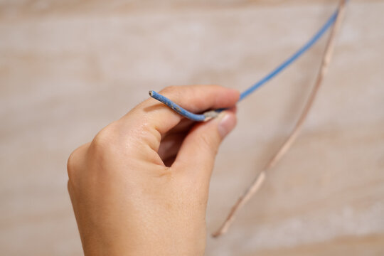 A woman's hand touches a bare wire