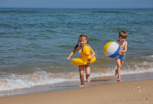Boy and girl enjoy a sunny summer day running along the ocean