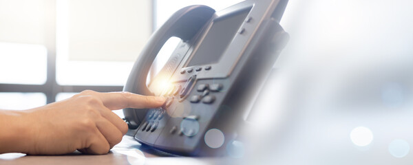 close up employee call center man hand point to press button number on telephone landline (VOIP...