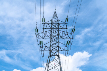 Electricity power pole with transmission lines against blue sky and clouds.