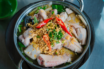 a hotpot filled with sour bamboo shoots and stingray pieces, garnished with herbs, showcasing a traditional Vietnamese dish. The broth is steaming, with vibrant colors and fresh ingredients.