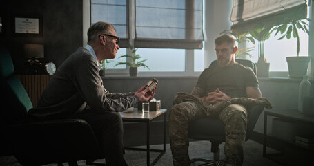 Senior psychiatrist talks to patient, gives antidepressants or sedative medicines to military man with PTSD. Psychotherapist conducts psychological therapy or post war rehabilitation for soldier.