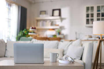 Laptop on the table with a cup of coffee and headphones for working in a comfortable living room.