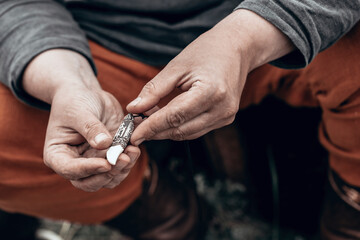 Male hands hold an authentic pendant in the form of an animal's fang with carvings and runes, close-up, selective focus.