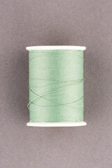 Green thread spool close-up macro flat lay top view.