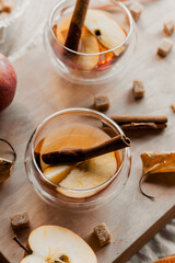apple tea in glass cups with red apple slices and cinnamon stick, autumn tea, autumn drink, tea with brown cane sugar, autumn composition, fruit tea