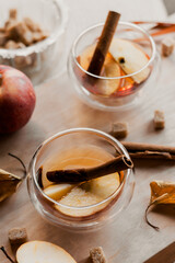 apple tea in glass cups with red apple slices and cinnamon stick, autumn tea, autumn drink, tea with brown cane sugar, autumn composition, fruit tea