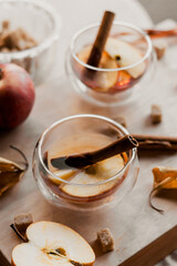 apple tea in glass cups with red apple slices and cinnamon stick, autumn tea, autumn drink, tea with brown cane sugar, autumn composition, fruit tea