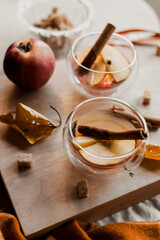 apple tea in glass cups with red apple slices and cinnamon stick, autumn tea, autumn drink, tea with brown cane sugar, autumn composition, fruit tea