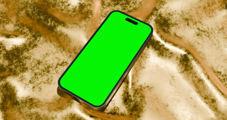 Smartphone with green screen display on textured golden fabric or sand background