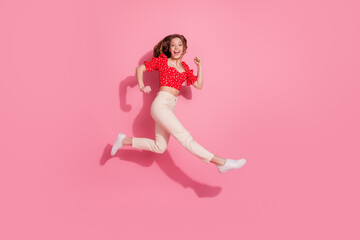 Full body photo of attractive teen woman running fast hurry dressed stylish red clothes isolated on pink color background