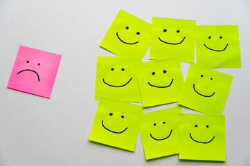 Colored sheets of paper, with smiley faces drawn on them, and next to them a sheet with a sad face...