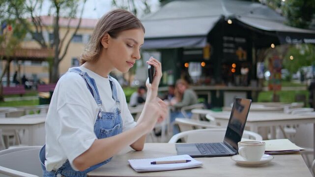 Woman journalist making notes in outdoors restaurant with cellphone closeup. 