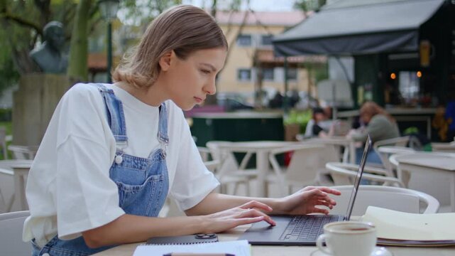 Focused student studying laptop at outdoors cafe closeup. Woman online research