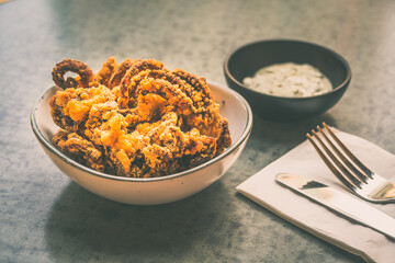 Fried Octopus  tentacles in a bowl with tartar sauce on the side