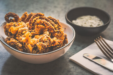 Fried Octopus  tentacles in a bowl with tartar sauce on the side
