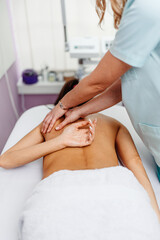 Fototapeta premium Beautiful young adult brunette receiving professional relaxation massage treatment at beauty spa salon.