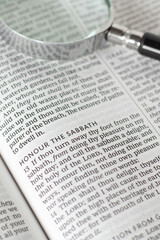 Obraz premium Honor the Sabbath verse in open holy bible book with magnifying glass. Christian biblical concept of seventh day rest, blessing, and obedience to God Jesus Christ.