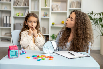 Female speech therapist working with a girl on her articulation