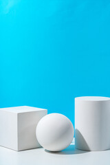Three geometric shapes arranged on a table against a bright blue background during daytime lighting