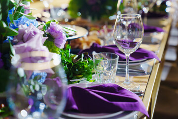 Beautiful festive table setting with flowers and purple napkins. 