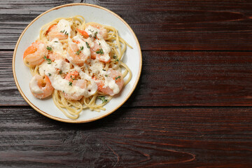 Tasty pasta with shrimps, creamy sauce and cheese on wooden table, top view. Space for text