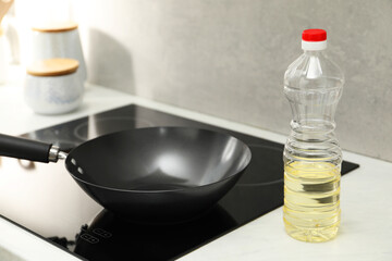 Frying pan and bottle of oil on cooktop in kitchen, closeup