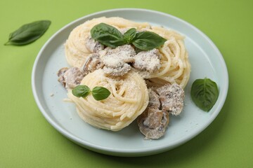 Delicious pasta with mushrooms and basil on light green background, closeup