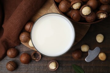 Glass of macadamia milk and nuts on wooden table, flat lay