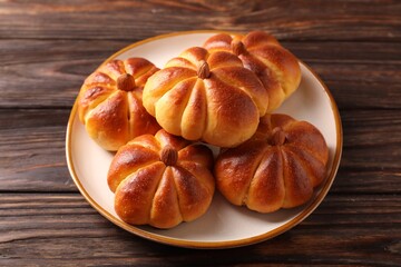 Tasty pumpkin shaped buns on wooden table, closeup