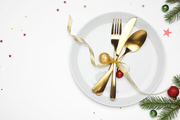 Christmas table setting with plate, cutlery and festive decor on white background, flat lay. Space...