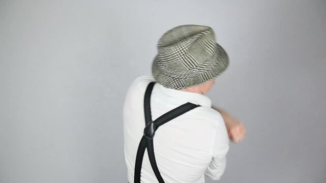 Vintage Detective in Suspenders and Fedora Rolling Up His Sleeves to Fight Himself. Funny Man Punching Himself Out.