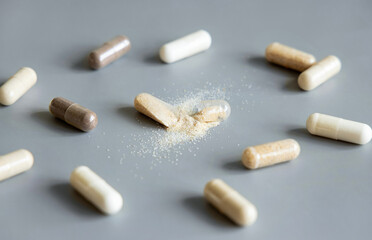 Opened Medical capsule to show beige powder on grey close up. Dietary supplements