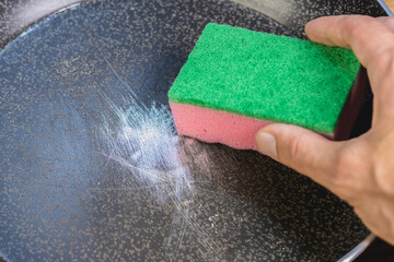 Sponge in hand for washing dishes in scratched teflon non stick coated pan. Dangerous chemicals in...