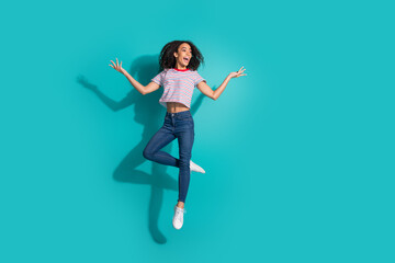 Full length photo of lovely young lady jump look empty space dressed stylish striped garment isolated on cyan color background