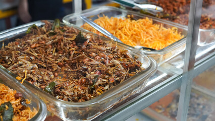 Food stalls called warteg share a variety of buffet traditional menus of indonesia with vegetables, chicken curry sauce, beef, eggs, tofu, tempeh. Menu in glass display case. 