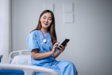 Smiling asian female doctor browsing on smartphone in hospital room