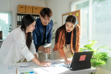 Asian business team analyzing charts and data on laptop in office meeting