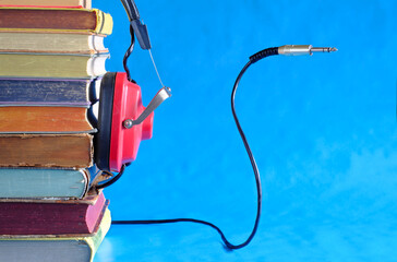 audiobooks concept with  books vintage headphonesand audio plug.Bright blue  background , free copy...