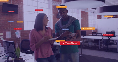 Image of social media icons with texts over diverse colleagues discussing work in office