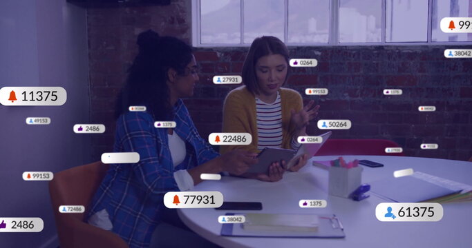 Image of social media icons with numbers over diverse colleagues discussing work in office