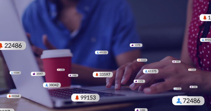 Image of social media icons with numbers over diverse colleagues discussing work in office