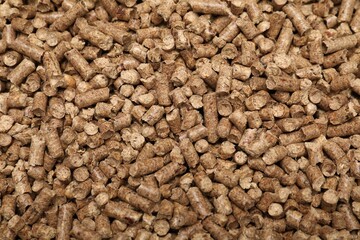 Wood pellet cat litter as background, top view
