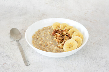 a bowl of oatmeal with banana slices and a spoon next to it