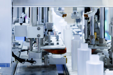 robot arm moving plastic bottle to conveyor belt of auto capping and labeling machine at cosmetic...