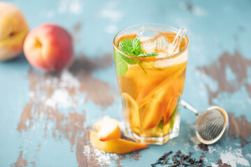 Fruit black iced tea with peaches and mint in a glass on the table. Summer drink concept