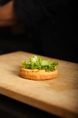 Stop motion of assembling burger. burber bon a chopping wood with Lettuce on it. 